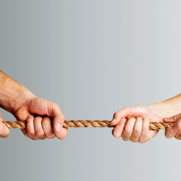 Two sets of hands pulling a rope 